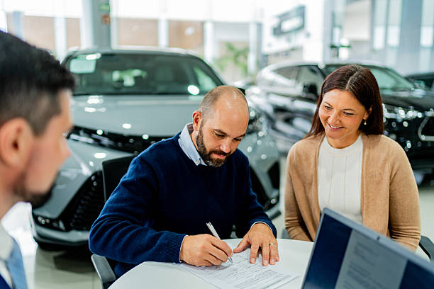 Couple signing documents at car dealership